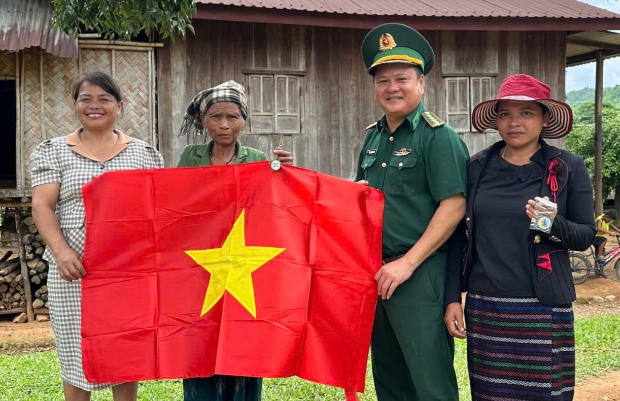 B&iacute; thư Đảng ủy x&atilde; Hướng Lập Hồ Thị Thiệt (ngo&agrave;i c&ugrave;ng b&ecirc;n tr&aacute;i) tặng cờ Tổ quốc cho người d&acirc;n th&ocirc;n S&ecirc; Pu - T&agrave; Păng - Ảnh: T.H